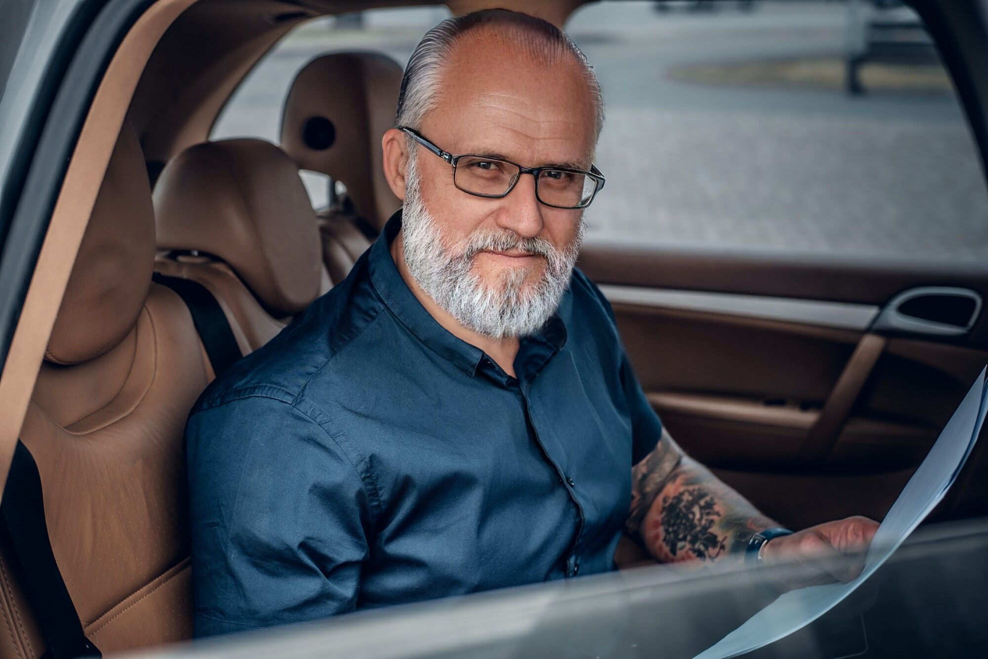 Photo d'un vieil homme d'affaires cool avec des documents en voyage à l'intérieur de la voiture.